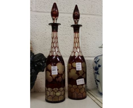 A pair of ruby coloured etched glass decanters (one neck repaired).