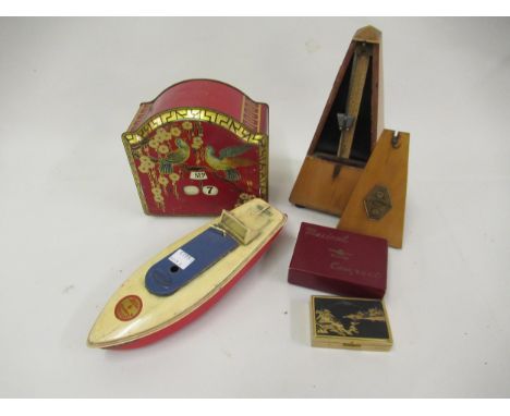 Sutcliffe tin plate model motor boat, a French metronome, a biscuit tin with calendar to the lid and a Clover musical compact