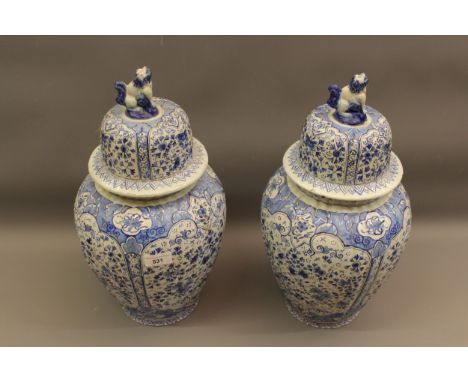 Pair of blue and white Delftware pottery vases with covers, with dog finials and all-over floral decoration, 17ins high 