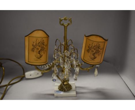 A vintage table lamp having lustre drops and twin candelabra style light fittings with paper shades.