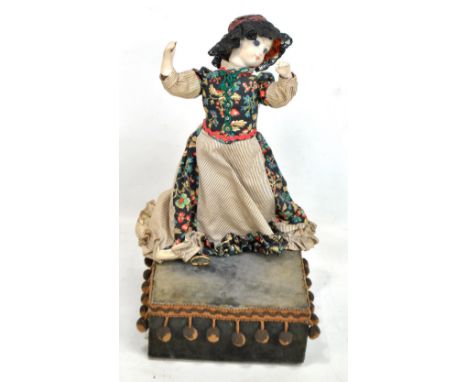 A musical clockwork automaton bisque headed doll with painted features, blue glass eyes and closed mouth in floral hat and dr