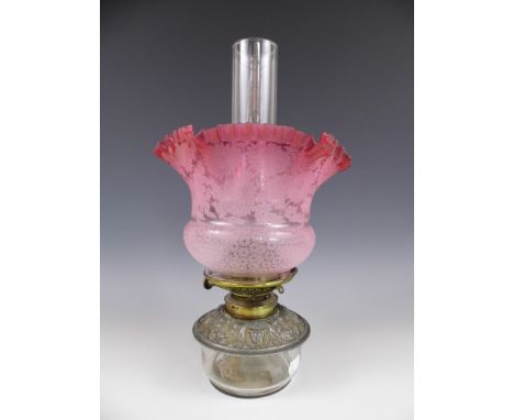 A Victorian oil lamp with etched achromatising cranberry glass shade
