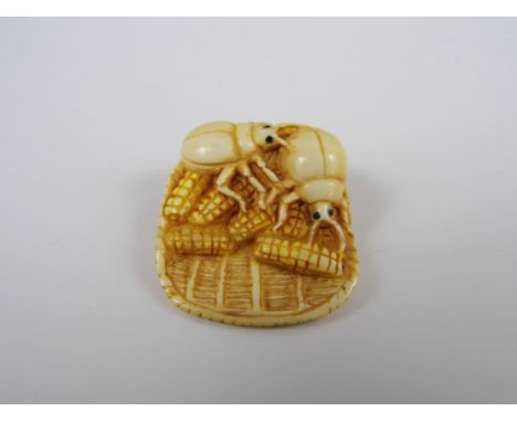 A signed Meiji Japanese ivory netsuke modelled as a basket of corn cobs with large beetles