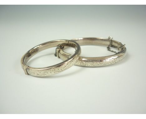 A child's silver hinged bangle, of hollow D section with foliate engraving, together with one other similar baby's bangle (2)