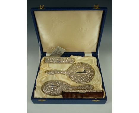 An Elizabeth II cased silver grooming set, comprising hand mirror and two brushes, together with an associated comb, the form