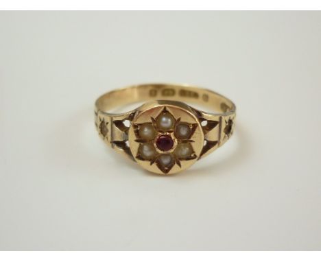 A Victorian 9ct gold, ruby and seed pearl dress ring, faced with a central raised disc bearing a gypsy-set flowerhead arrange