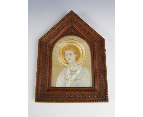A late 19th Century embroidered silk and bullion depiction of a saint, in an elaborately carved wooden pointed-arch frame, 35