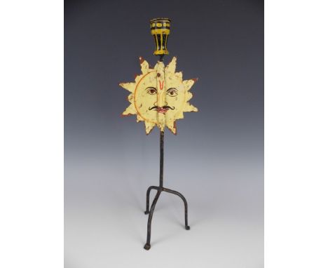 A folk art painted wrought iron candlestick, the socket supported on a slender wire tripod support faced by a planar depictio