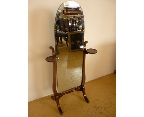 A mahogany cheval mirror, having a slender arched mirror plate supported in a lyre-form support incorporating circular lamp o