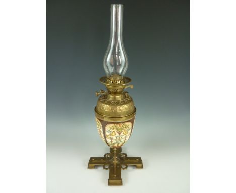A Victorian Arts and Crafts inspired ceramic and brass oil lamp, having a geometric and arcade embossed brass reservoir, supp