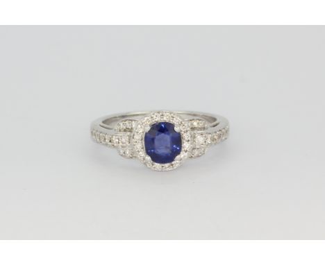 A hallmarked white gold ring set with an oval cut sapphire and brilliant cut diamonds, (M.5).