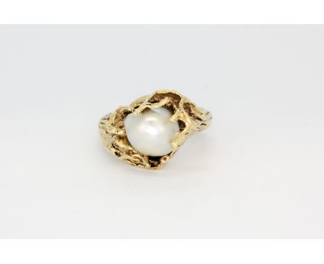 A heavy yellow metal (tested 14ct gold) ring set with a large natural baroque pearl, (L), approx. 10.7gr.