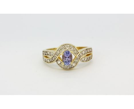 A 14ct yellow gold (stamped 14k) ring set with an oval cut tanzanite and diamonds, (O).