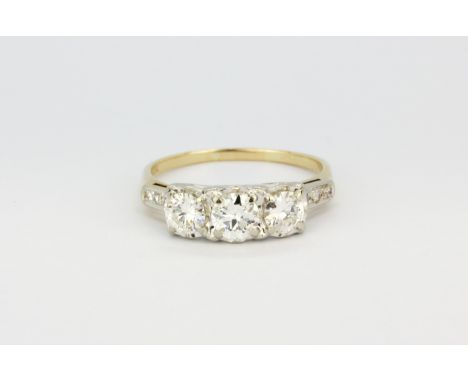 A 14ct yellow and gold (stamped 14) three stone ring set with three large brilliant cut diamonds and diamond set shoulders, a