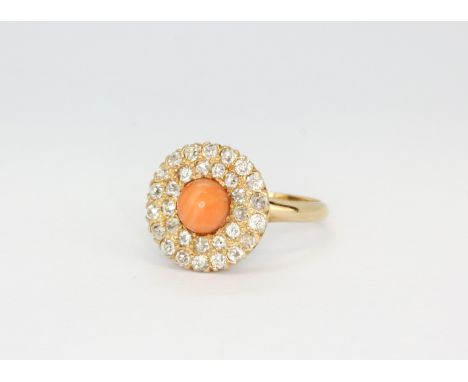 An 18ct yellow gold ring set with a cabochon cut coral surrounded by diamonds, (L).