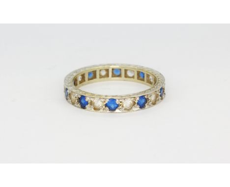 A hallmarked 9ct white gold eternity ring set with round cut synthetic spinels, (Q).