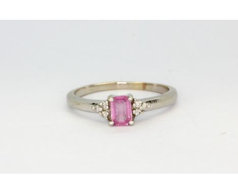 A 14ct white gold (stamped 14k) solitaire ring set with an emerald cut pink sapphire and diamond set shoulders, (U), approx. 