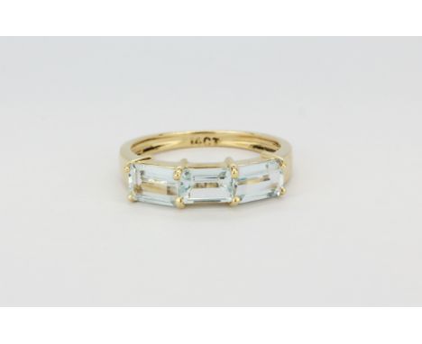 A 14ct yellow gold (stamped 14k) ring set with three emerald cut aquamarines, (M).