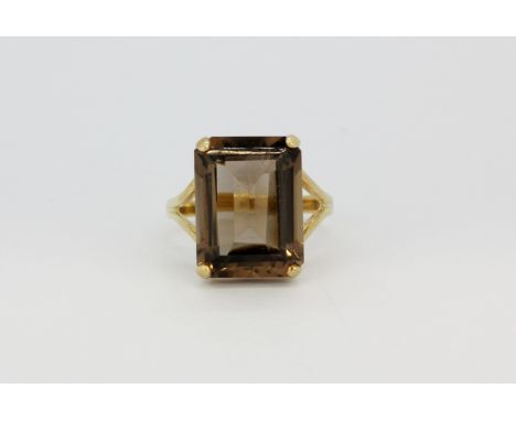 A 10ct yellow gold (stamped 10k) open shoulder ring set with a large emerald cut smokey quartz, (O).