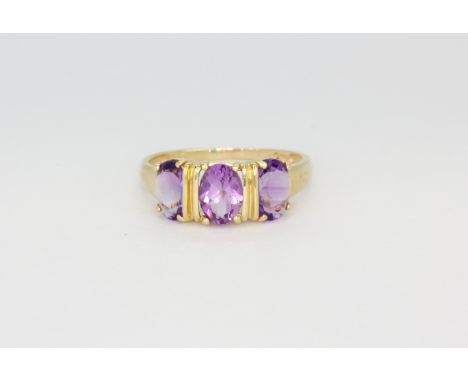 A 14ct yellow gold (stamped 14k) ring set with three oval cut amethysts, (P.5).