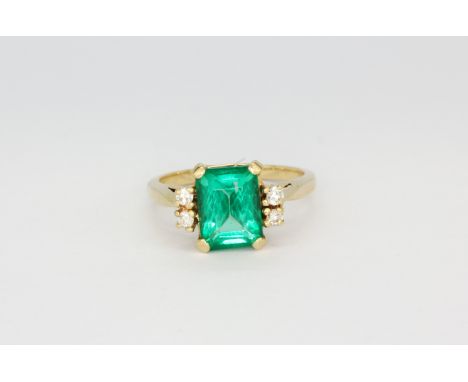 A 14ct yellow gold (stamped 14k) ring set with a large emerald cut emerald and brilliant cut diamonds, (L)