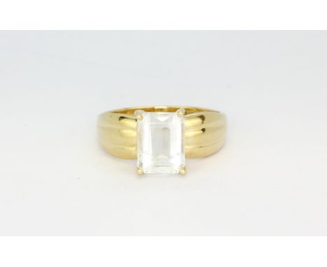 A 14ct yellow gold (stamped 14k) solitaire ring set with an emerald cut aquamarine, (O).