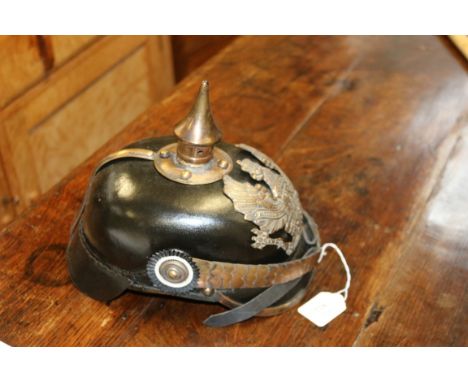 A brass mounted and shaped leather pickelhaube helmet, with chin strap and black finish, fitted with a spear form spike