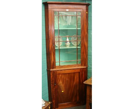 A 19th century mahogany floor standing corner cupboard, the moulded cornice over glazed door enclosing two shelves above a pa