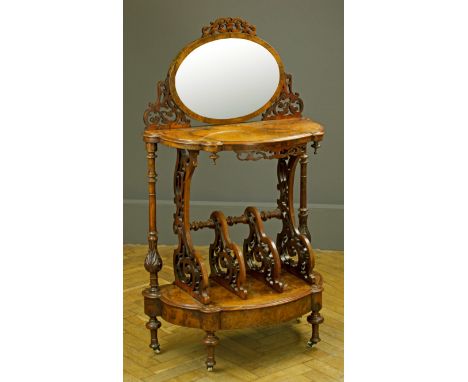 A Victorian figured walnut canterbury whatnot, having a fret carved surround mirror over two stages with divided undertier an