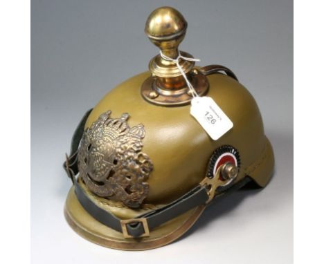 A brass mounted and shaped leather pickelhaube helmet, with chin strap and khaki finished, fitted with a pommel finial