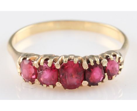 A yellow metal ruby five stone ring, the five stones graduating in size, the central largest stone measuring approx. 5x4mm, u