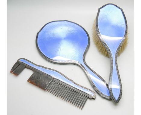 A silver and blue enamelled hand mirror with black enamelled border and with matching brush and comb holder, Birmingham 1928,