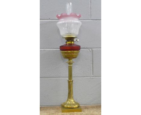 An Art Nouveau brass oil lamp with ruby glass reservoir 