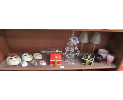 A shelf of miscellaneous including decorated face masks, ship in bottle etc