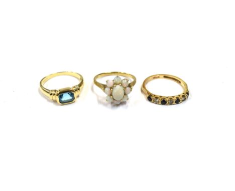 9CT GOLD GEM SET RINGS To include a white opal cabochon floral cluster, an octagonal step cut blue topaz and a round sapphire