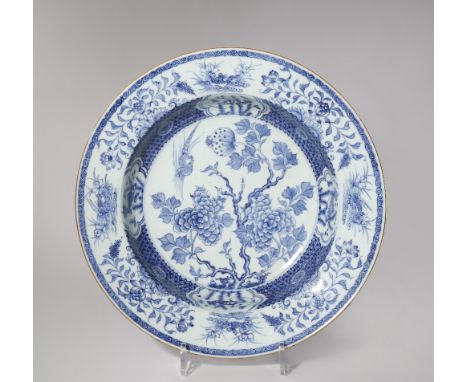 A CHINESE BLUE AND WHITE SHALLOW BASIN 18TH CENTURY Painted with a pheasant in flight above a peony bush, with panels of fish