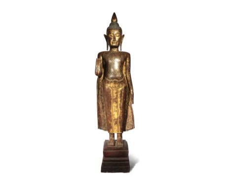 A CAMBODIAN LACQUERED AND PARCEL-GILT WOOD FIGURE OF BUDDHA 19TH/20TH CENTURY Depicted standing in samabhanga on a lacquered 