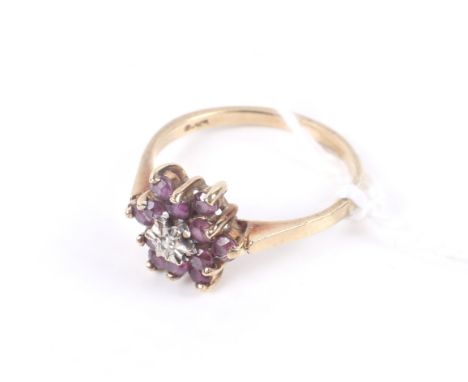 A vintage 9ct gold, ruby and diamond cluster ring. Centred with a small eight-cut diamond within a round mixed-cut ruby twelv