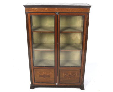 An Edwardian mahogany display cabinet. With a cornice and glazed doors inlaid with ribbon festoons, on bracket supports, H136