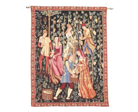 A reproduction tapestry panel. Woven with a scene of medieval characters in a vineyard preparing wine, within a red border, b