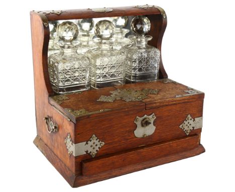 An Edwardian 3 decanter oak tantalus, Gothic metal mounts, with glass cabinet, cribbage board drawer and mirror back.I decant