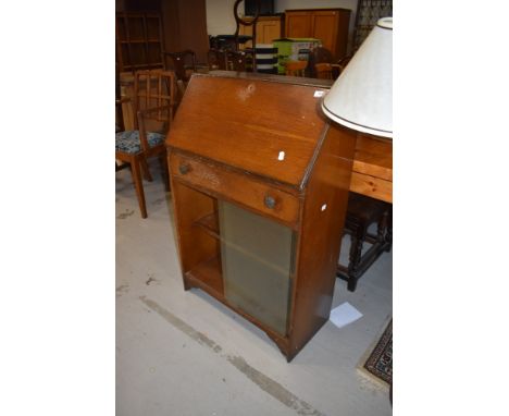 An oak bureau having glass book shelf under