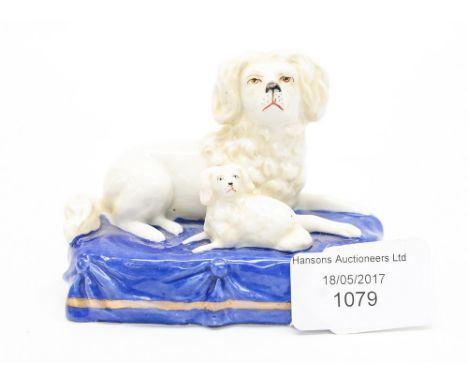 A ceramic figure of a dog and puppy on a blue plinth.