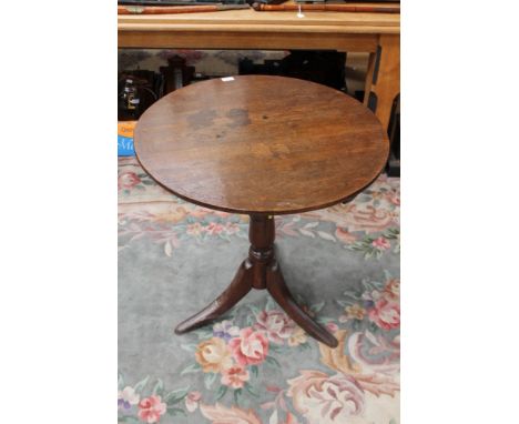 A George III oak tripod table, the plank top raised on a turned column and standing on three sabre legs