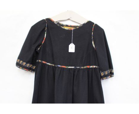 A mid 1970s black wool dress by design label Francess Haigh, decorated with cotton floral edging on the neckline, sleeves, pa