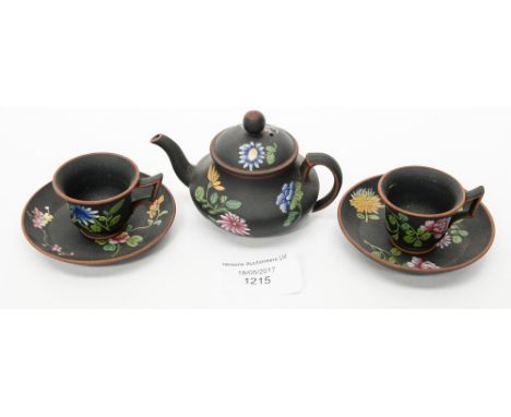 A miniature Wedgwood black baslat teapot and two tea cups and saucers, with polychrome enamel decoration, 19th Century, impre