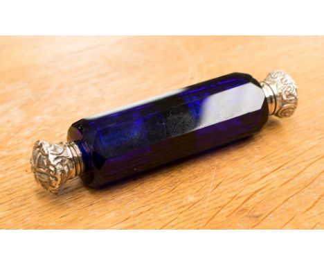 A Victorian blue glass perfume bottle toped with white metal caps, probably silver, with a leaf  continental design. The tota