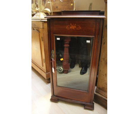 An Edwardian mahogany music cabinet, fitted with a single door enclosing fitted shelves, raised on bracket feet, together wit