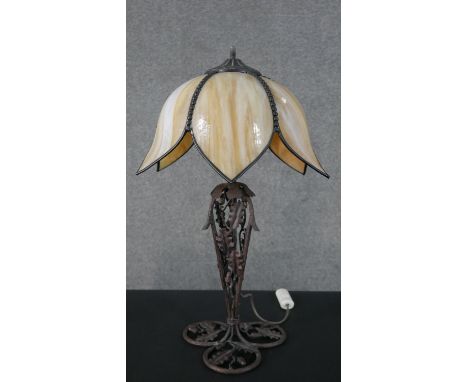 A table lamp with leaded floral form opaque glass shade on a naturalistic scrolling metal base. H.55 W.36cm 