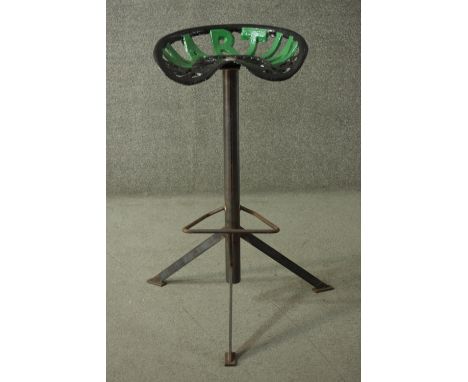 A painted cast iron tractor seat stool, with 'Martin' to the rear, on a scaffold type support with tripod feet. 